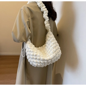 Detail of white bubble texture nylon shoulder bag with soft quilted strap on a trench coat
