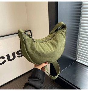 Detail of olive green crescent bag showing nylon fabric texture and zipper closure