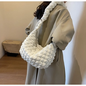 Detail of white quilted bubble texture nylon shoulder bag shown on model with trench coat