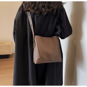 Brown lychee leather bucket bag with adjustable strap and vintage textured finish