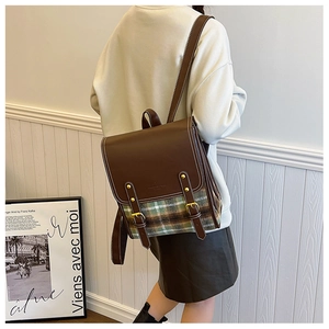 Side view of vintage British style brown leather and plaid flannel backpack on model