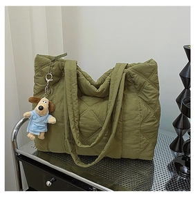 Close-up of green quilted nylon tote bag with plush dog charm on a silver metal cart