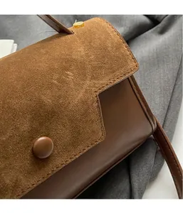 Detail of vintage brown suede and leather handbag with round buckle and gold rivet studs