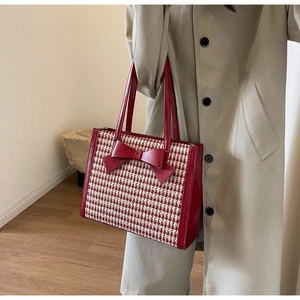 Dettaglio borsa tote pied-de-poule rossa con grande fiocco in pelle sulla spalla