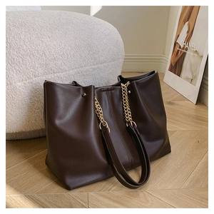 Close-up of brown litchi pattern tote bag with metal rivets and chain strap detail