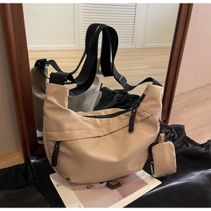 Detail of beige nylon half-moon crossbody bag with woven zipper pull and small coin purse