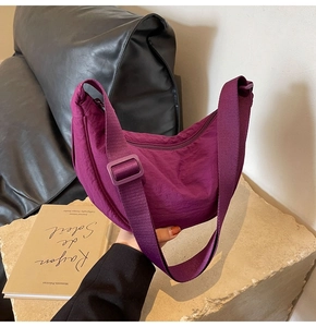 Detail of purple crescent shoulder bag featuring water-resistant nylon texture and strap