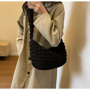 Detail of black quilted bubble texture nylon hobo bag shown on a model's shoulder