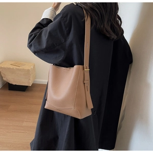 Detail view of camel leather bucket bag showing adjustable strap and pebble grain texture