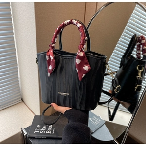 Detailed view of black pleated tote bag with red heart patterned silk scarf wrapped handle