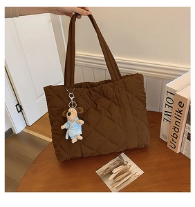 Close-up of brown quilted nylon tote bag with a cute puppy plush charm on a wooden table