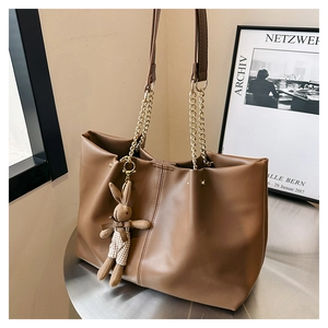 Close-up of brown PU leather tote bag with gold chain strap and cute rabbit pendant