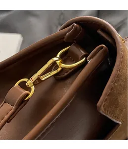 Close-up of bright gold hardware hook and D-ring on a brown leather and suede handbag