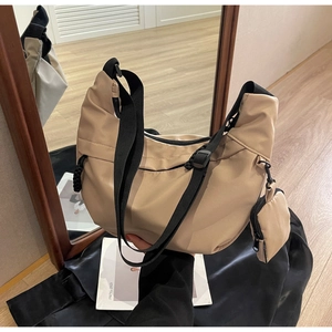 Detail of beige nylon crossbody bag with mini pouch on black satin fabric background