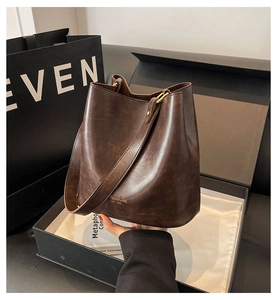 Close-up of vintage brown leather bucket bag in premium packaging with gold lettering
