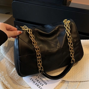 Chic black quilted tote bag with geometric stitching and gold chain straps on white knit
