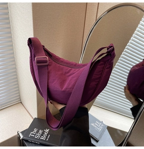 Detailed view of the adjustable wide strap and purple crescent nylon bag