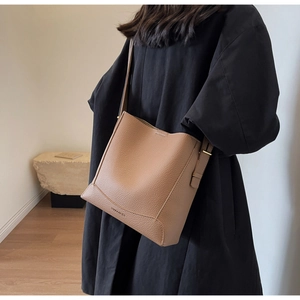 Detail of a brown lychee-patterned bucket bag with adjustable strap and side stitching