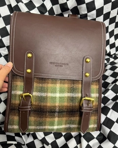 Detail of vintage plaid backpack with dark brown leather flap and golden buckle hardware