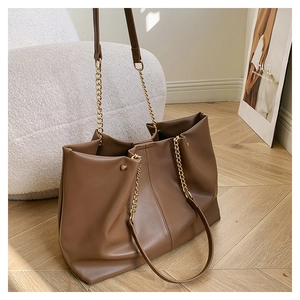 Detail of brown faux leather tote with gold chain strap and soft pleated texture