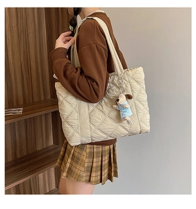 Detail of beige quilted nylon tote bag with plush puppy charm and diamond pattern