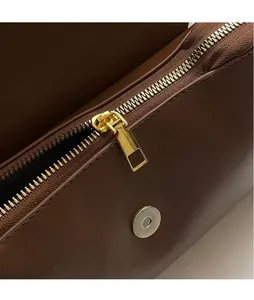 Detailed close-up of premium gold hardware, zipper, and magnetic snap on a brown leather bag