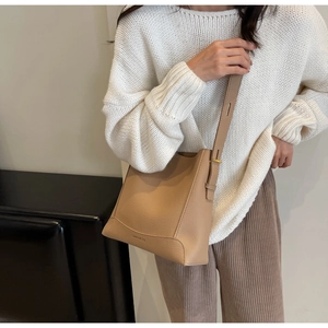 Detail of beige lychee pattern leather bucket bag with adjustable strap and gold hardware