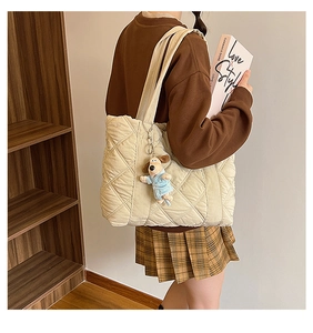Detail of beige quilted nylon tote bag with rhombus pattern and cute dog plush pendant