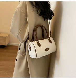 Détail du sac polochon en peluche blanche avec poignées en cuir marron et logo