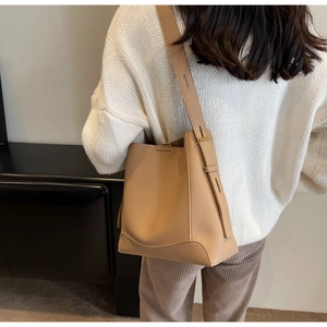 Detail of adjustable wide shoulder strap on beige lychee leather bucket bag