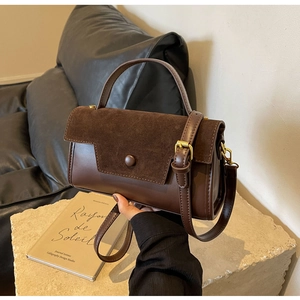 Detail of vintage brown leather handbag showing mixed suede texture and gold buckle