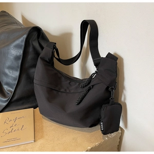 Detail of black nylon crescent messenger bag with adjustable strap and small coin pouch