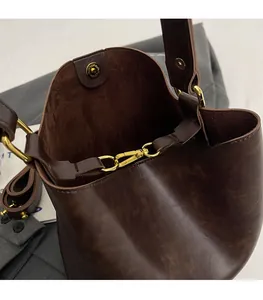 Close-up of vintage brown leather bucket bag with gold hardware and magnetic snap button