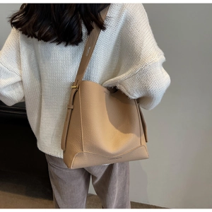 Detail view of khaki pebbled leather bucket bag with wide strap and embossed logo