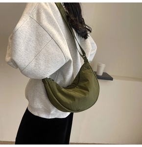 Detail of army green nylon half-moon crossbody bag showing fabric texture and strap