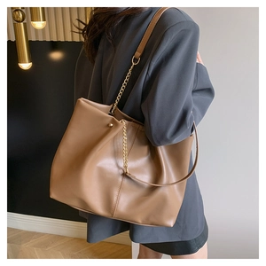Detail of khaki brown PU leather tote bag with gold chain strap worn with a grey blazer