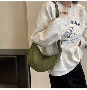 Detailed view of the grass green crescent crossbody bag worn with casual streetwear outfit