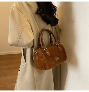 Détail d'un sac en peluche marron avec poignées en cuir et garnitures en métal doré