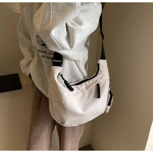 Detail of off-white nylon hobo bag with wide black strap and cord zipper pull