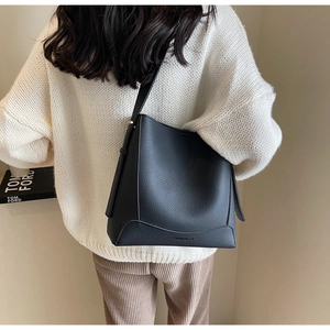 Close-up of black lychee grain leather bucket bag featuring embossed brand logo detail