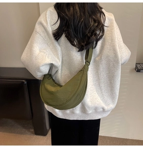 Detail view of olive green crescent nylon crossbody bag worn on a model's back