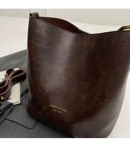 Detail view of dark brown leather bucket bag showing textured surface and fashion logo