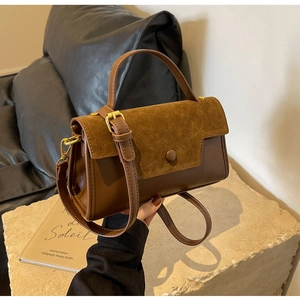 Close-up of brown vintage handbag featuring smooth leather and suede patchwork with gold hardware