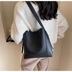 Detail of black pebbled leather tote bag showing fine stitching and bucket silhouette