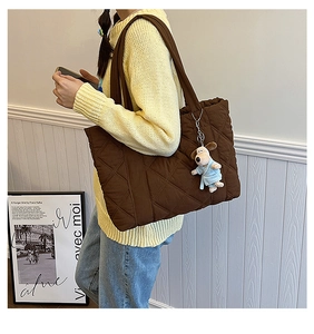 Brown quilted nylon tote bag with large diamond stitching worn by a female model