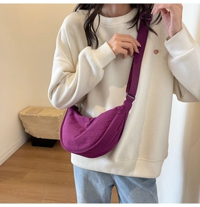 Detailed macro view of the textured purple crescent bag with adjustable wide shoulder strap