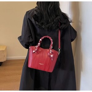 Detail of red leather handbag with wave embossing and heart pattern scarf on handle