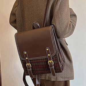 Retro plaid patchwork backpack with brown leather straps and gold buckle worn on a blazer