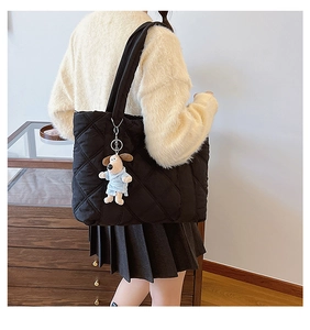 Close-up of black quilted nylon tote bag with a cute cartoon dog plush charm detail