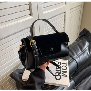 Detail of black faux leather and suede handbag with gold buckle and top handle